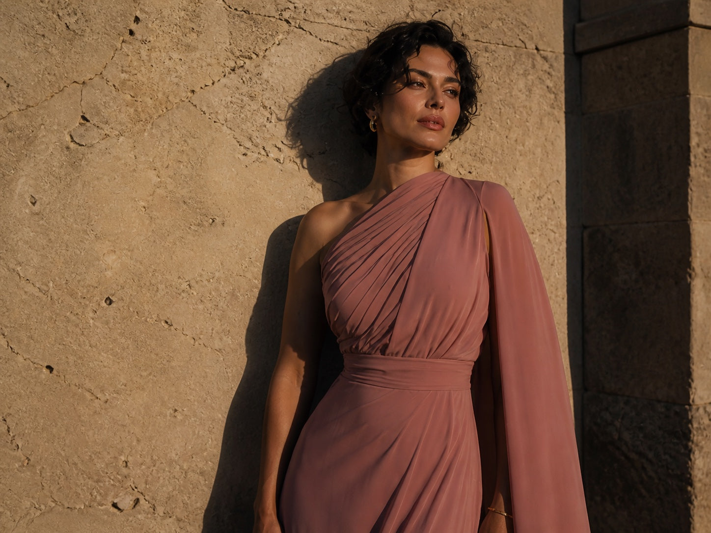 Monci model in a dusty rose gown beside an Adriatic stone wall